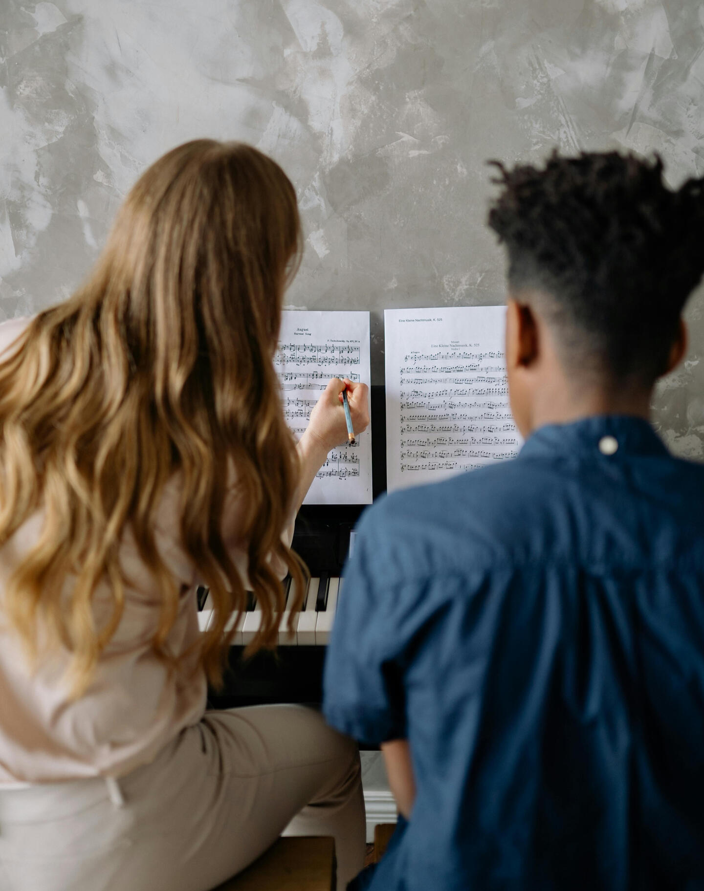 An image teacher explaining music theory concepts to a student over the piano An image teacher explaining music theory concepts to a student over the piano